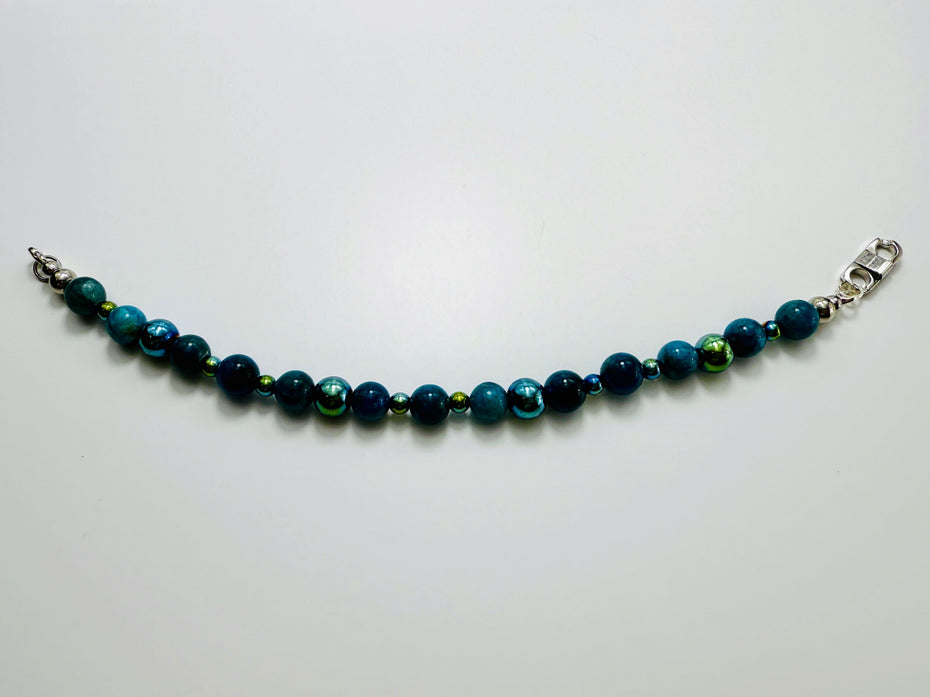 Armband aus blauen Apatit-Perlen und facettiertem Hämatit auf weißem Hintergrund, aufgefächert dargestellt.