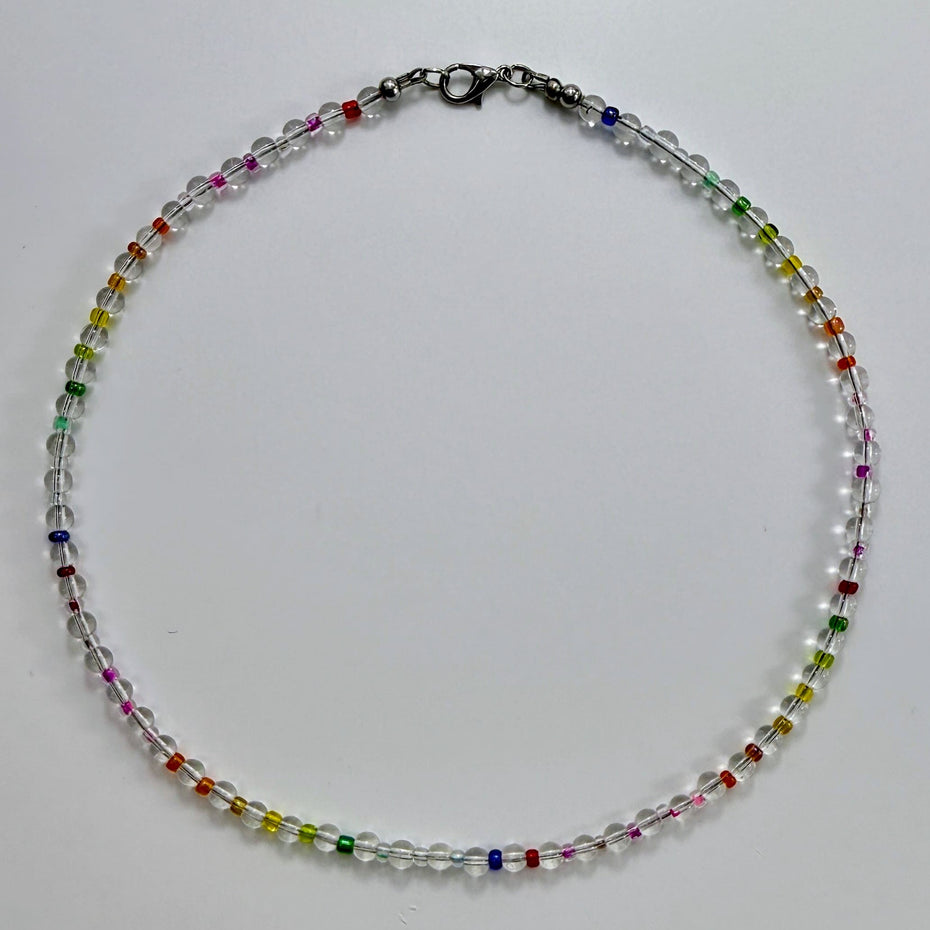 Zierliche Bergkristall-Halskette mit bunten Rocaille-Perlen in Regenbogenfarben, fotografiert in Draufsicht