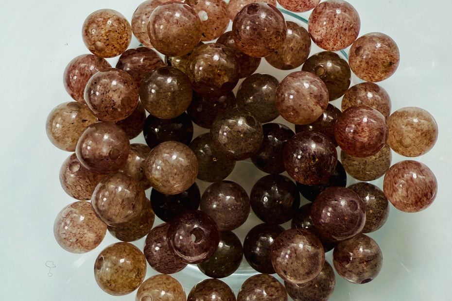 Runde Erdbeerquarz-Perlen mit rötlich-braunem Schimmer und feinen Einschlüssen, natürlich glänzend und ideal für energetischen Schmuck.