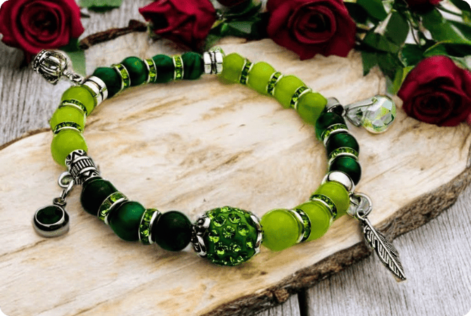Frühlingshaftes Damenarmband mit strahlend grünen Perlen, glitzernden Strass-Elementen und filigranem Feder-Anhänger. Handgefertigt in der Schweiz, ideal für leichte Frühlingsoutfits.