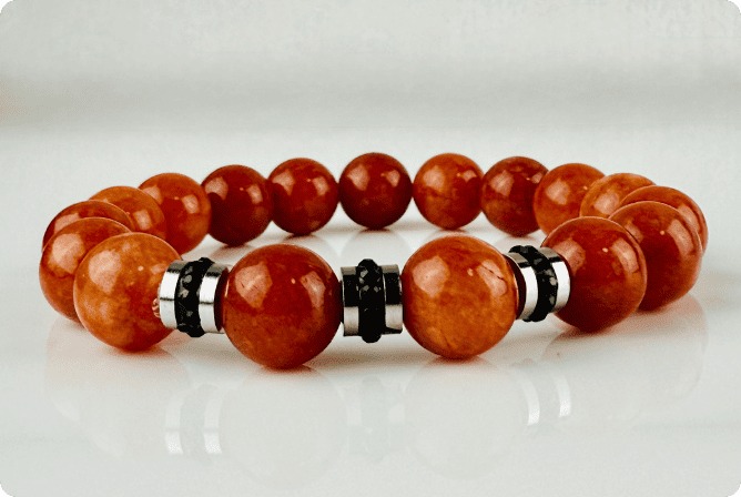 Handgefertigtes Armband mit leuchtenden Karneol-Quarz-Perlen in Orange-Rot, verziert mit eleganten Edelstahl-Elementen und funkelnden schwarzen Kristallakzenten. Ein modernes Accessoire mit lebendigen Farben und hochwertiger Verarbeitung.
