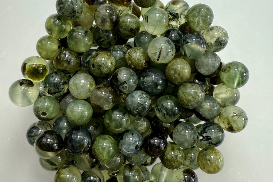 Runde grüne Prehnit-Perlen mit natürlichen Einschlüssen, glänzend poliert und durchscheinend – ideal für handgefertigten Schmuck.