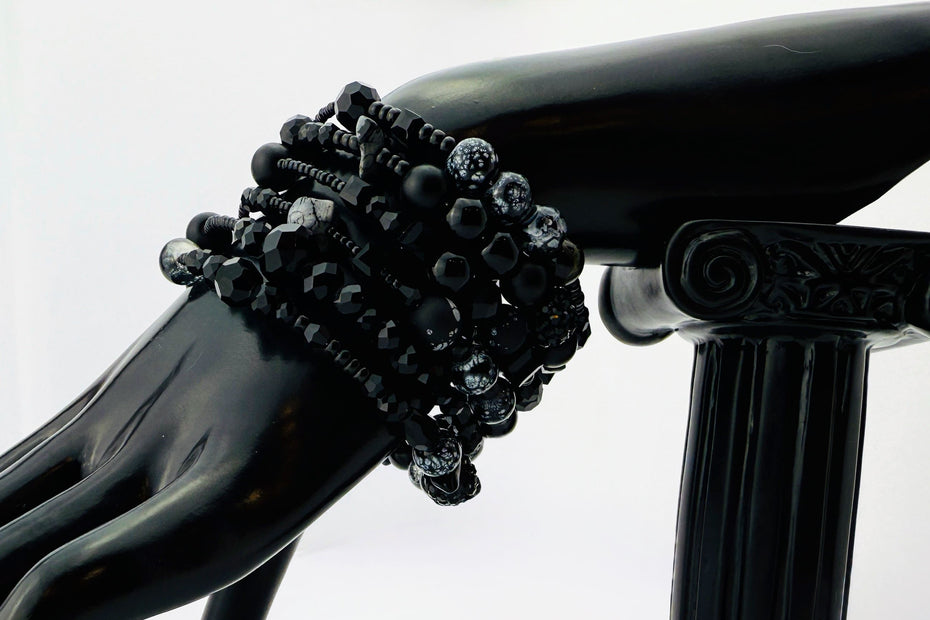 Elegantes spiralförmiges Armband mit einer vielseitigen Kombination aus schwarzen Glasperlen in verschiedenen Größen und Oberflächen. Handgefertigt in der Schweiz, flexibel ohne Verschluss, perfekt für stilvolle Alltagslooks und besondere Anlässe.