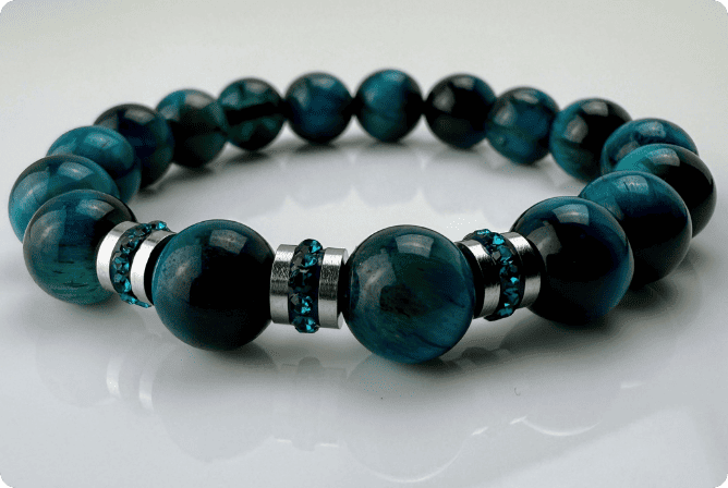 Blaugrünes Tigeraugen-Armband mit funkelnden Kristall-Edelstahl-Elementen, handgefertigt in der Schweiz. Vielseitiges und elegantes Design, das Strapazierfähigkeit und Stil vereint.