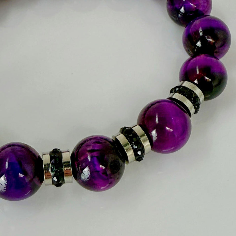 Lila Tigeraugen-Armband mit funkelnden schwarzen Kristallelementen in Edelstahlfassungen, handgefertigt in der Schweiz. Kraftvolles und elegantes Design, perfekt für jeden Anlass.