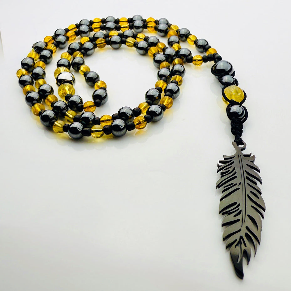 Handgefertigte Y-Halskette für Herren mit gelbem Citrin, Hämatit-Perlen und einem eleganten Edelstahl-Federnanhänger. Kunstvolle Makramee-Technik und schwarze Rocailles ergänzen das moderne und stilvolle Design.