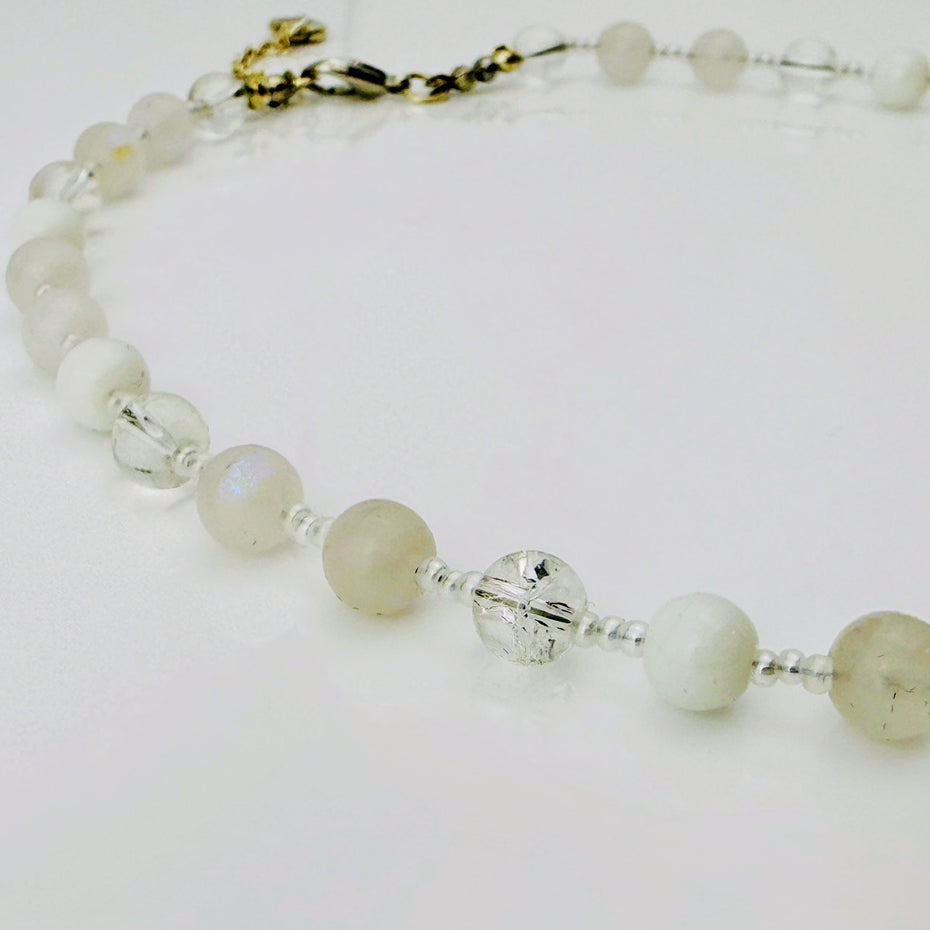 Zierliche Damenhalskette aus Mondstein- und Achatperlen, kombiniert mit transparent-weißen Rocailles. Handgefertigtes Schmuckstück aus der Schweiz, ideal für minimalistische und elegante Outfits.