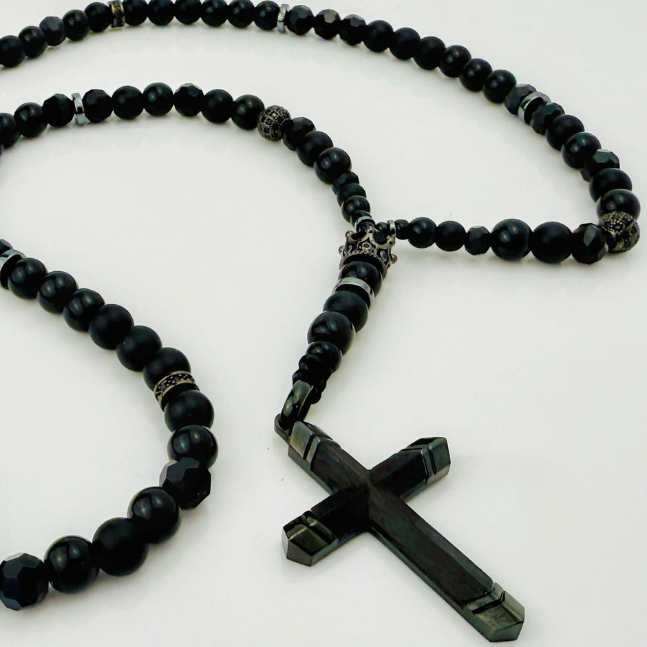Luxuriöse schwarze Perlenkette mit glänzenden Edelstahlelementen und markantem Kreuzanhänger.