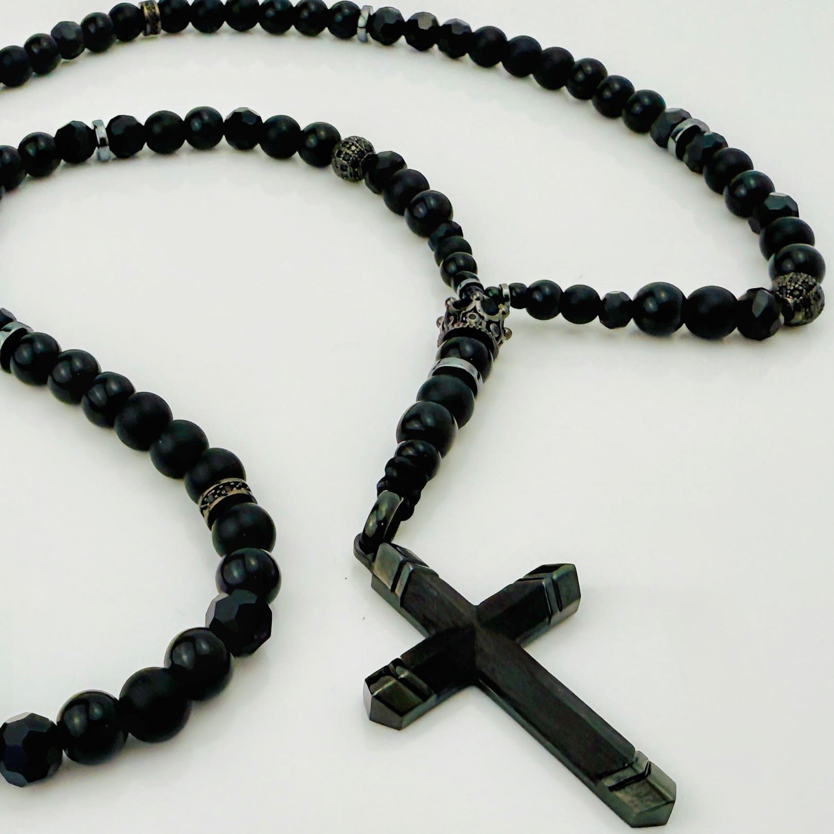 Luxuriöse schwarze Perlenkette mit glänzenden Edelstahlelementen und markantem Kreuzanhänger.