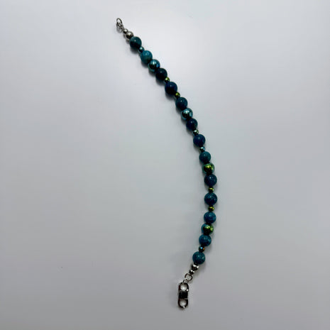 Armband mit Apatit- und Hämatitperlen in moderner Perspektive, auf hellem Untergrund.