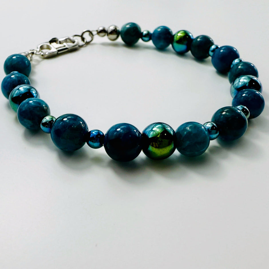 Armband aus blauen Apatit-Perlen und facettiertem Hämatit auf weißem Hintergrund, aufgefächert dargestellt.