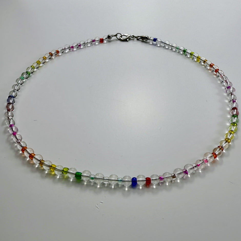 Zierliche Bergkristall-Halskette mit bunten Rocaille-Perlen in Regenbogenfarben, fotografiert in Draufsicht