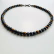 Runde Ansicht der Hämatit-Kette mit gleichmässigem Wechselspiel aus Schwarz und Goldbraun.