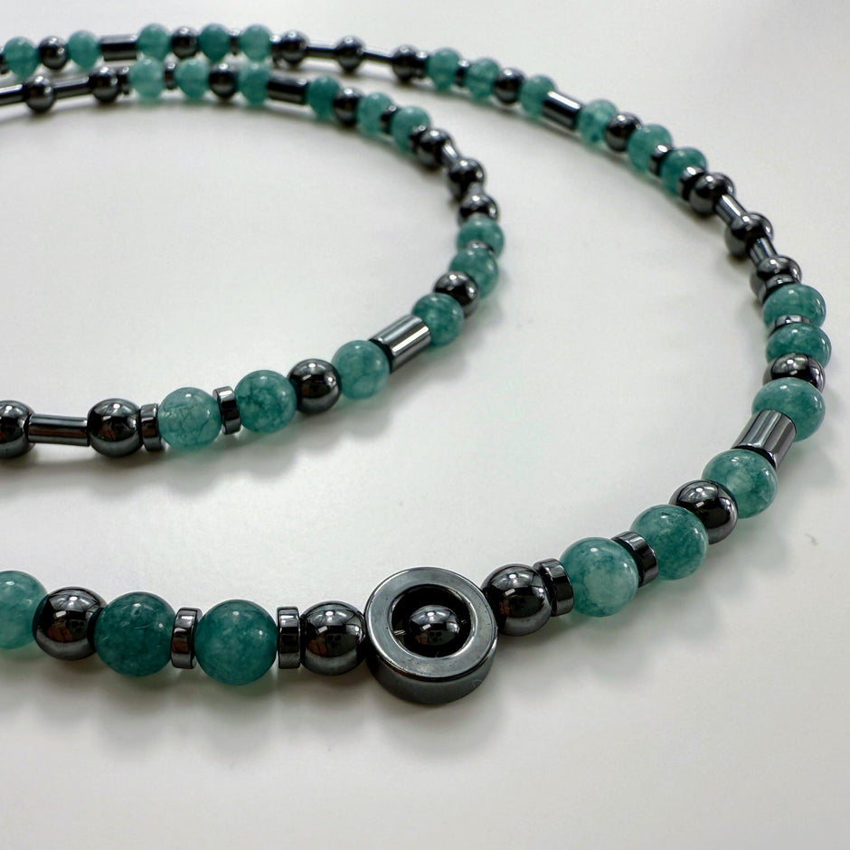 Schweizer Design: zarte Aquamarin- und Edelstahlkette auf hellem Hintergrund ausgebreitet.