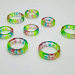 Handgefertigter Epoxid-Harz-Ring mit fluoreszierenden Steinen in Grün, Blau und Rosa – einzigartiges Schmuckstück.