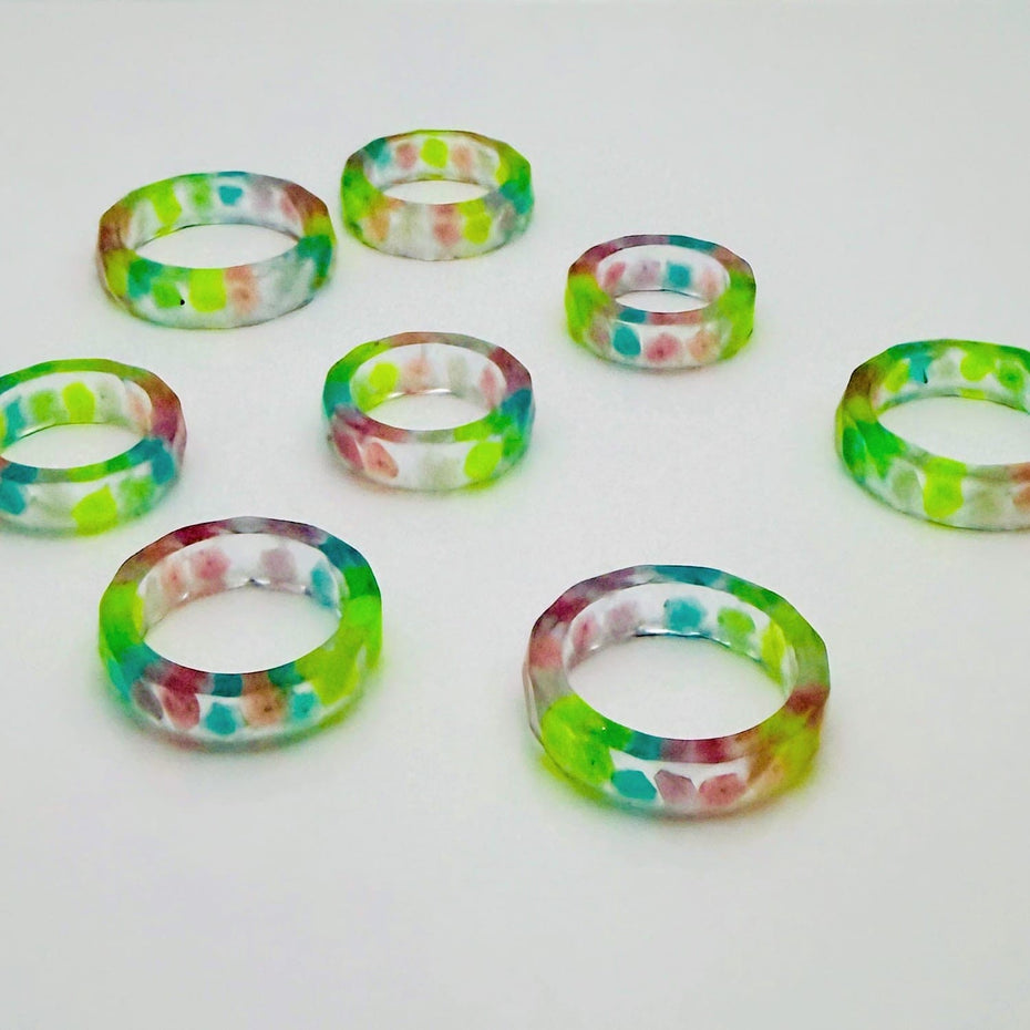 Handgefertigter Epoxid-Harz-Ring mit fluoreszierenden Steinen in Grün, Blau und Rosa – einzigartiges Schmuckstück.