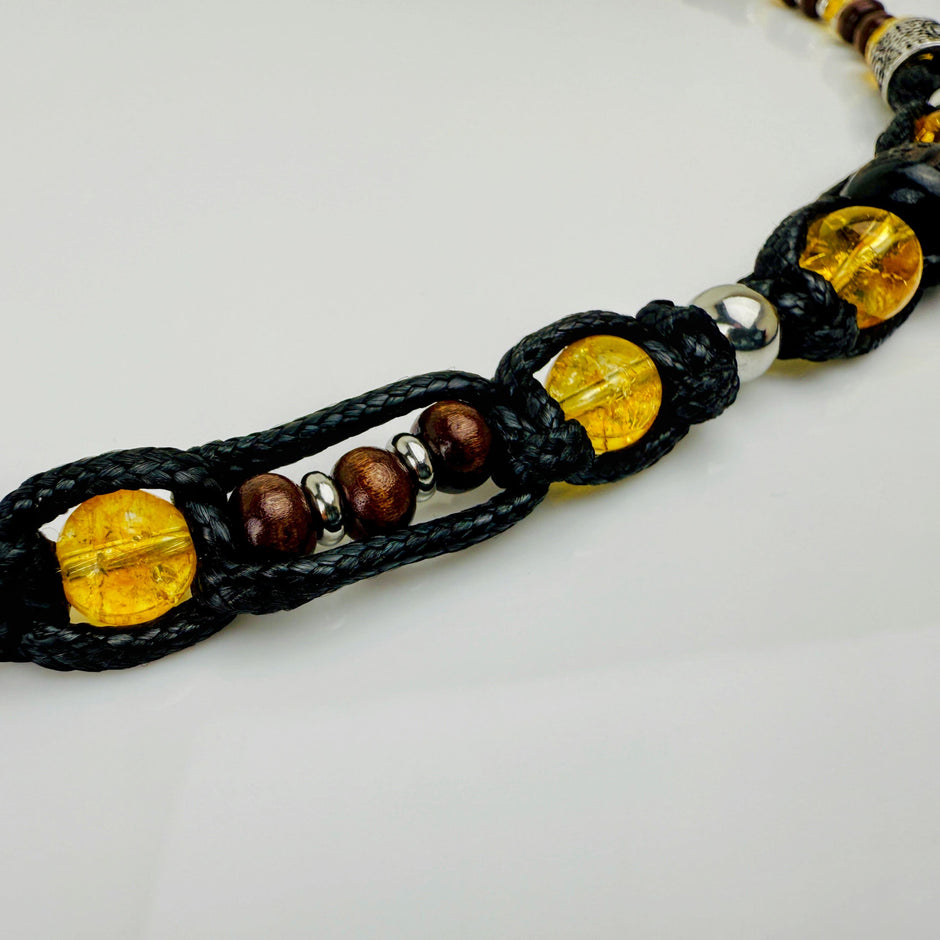 Handgeknüpfte Makramee-Kette mit funkelnden Citrin-Steinperlen, edlen Edelstahlelementen und einem kunstvoll verzierten Runenanhänger. Schweizer Schmuckstück, das Eleganz und Mystik verbindet.