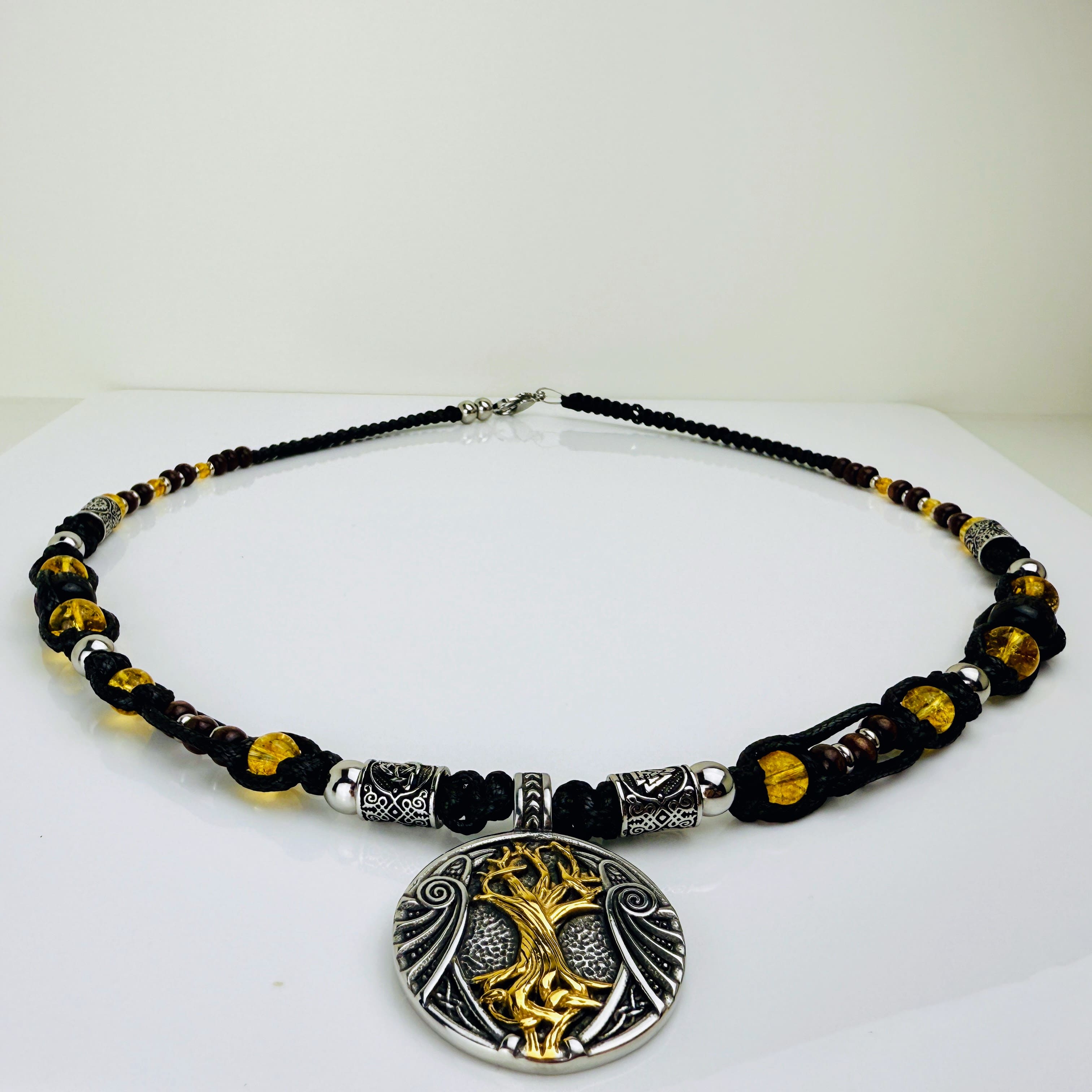 Handgeknüpfte Makramee-Kette mit funkelnden Citrin-Steinperlen, edlen Edelstahlelementen und einem kunstvoll verzierten Runenanhänger. Schweizer Schmuckstück, das Eleganz und Mystik verbindet.
