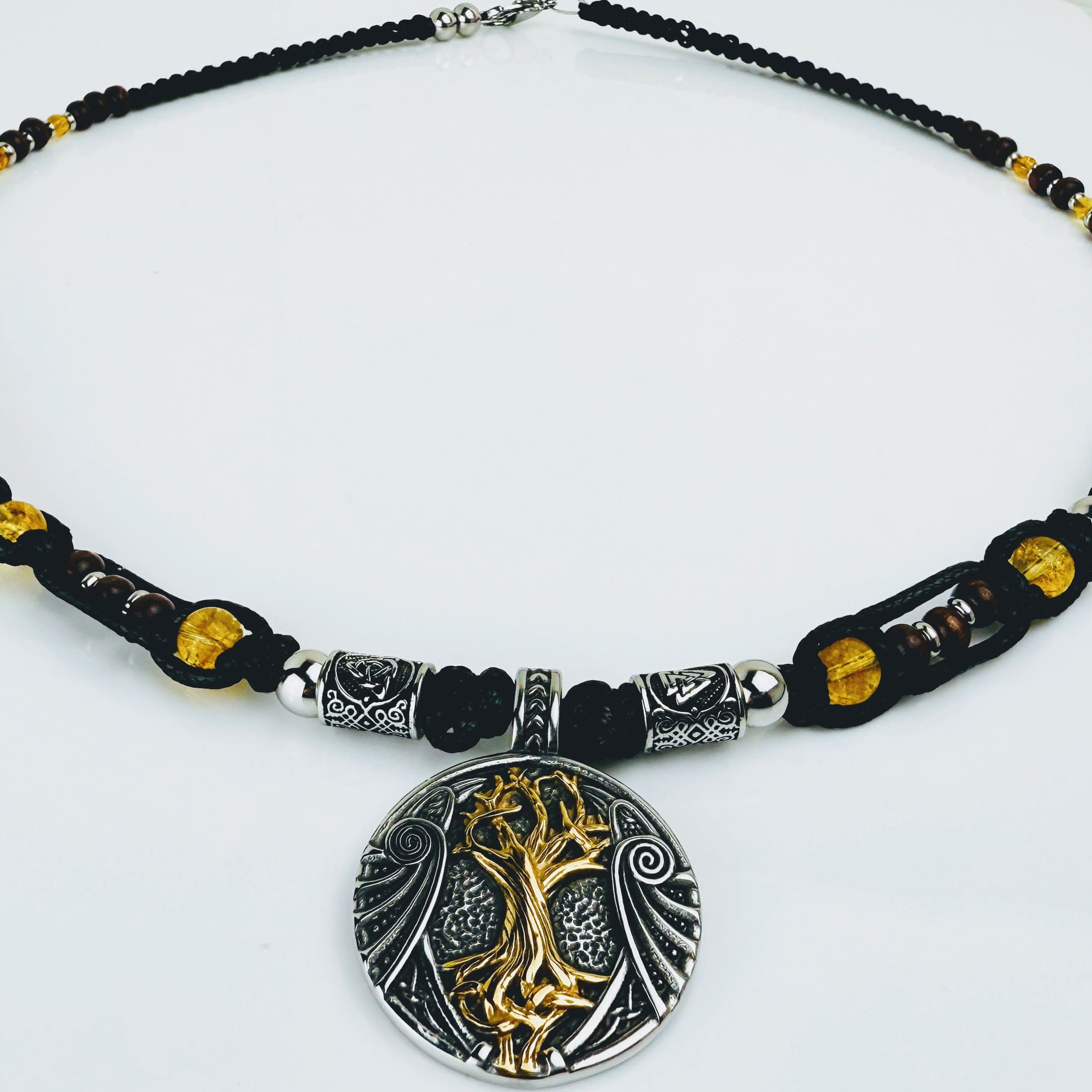 Handgeknüpfte Makramee-Kette mit funkelnden Citrin-Steinperlen, edlen Edelstahlelementen und einem kunstvoll verzierten Runenanhänger. Schweizer Schmuckstück, das Eleganz und Mystik verbindet.