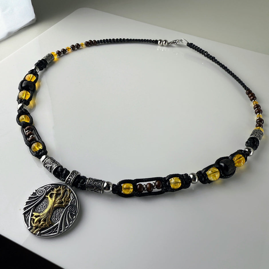 Handgeknüpfte Makramee-Kette mit funkelnden Citrin-Steinperlen, edlen Edelstahlelementen und einem kunstvoll verzierten Runenanhänger. Schweizer Schmuckstück, das Eleganz und Mystik verbindet.