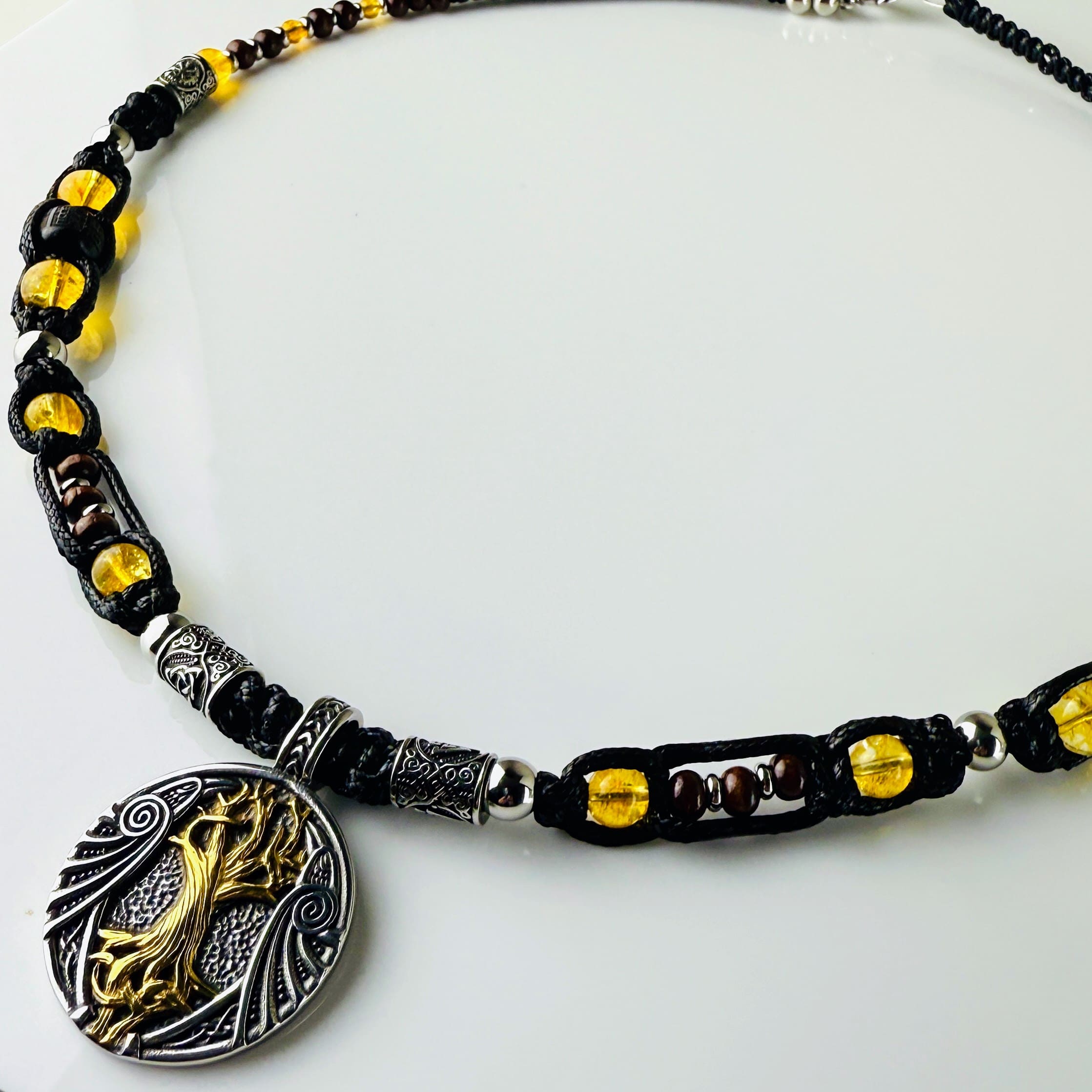 Handgeknüpfte Makramee-Kette mit funkelnden Citrin-Steinperlen, edlen Edelstahlelementen und einem kunstvoll verzierten Runenanhänger. Schweizer Schmuckstück, das Eleganz und Mystik verbindet.