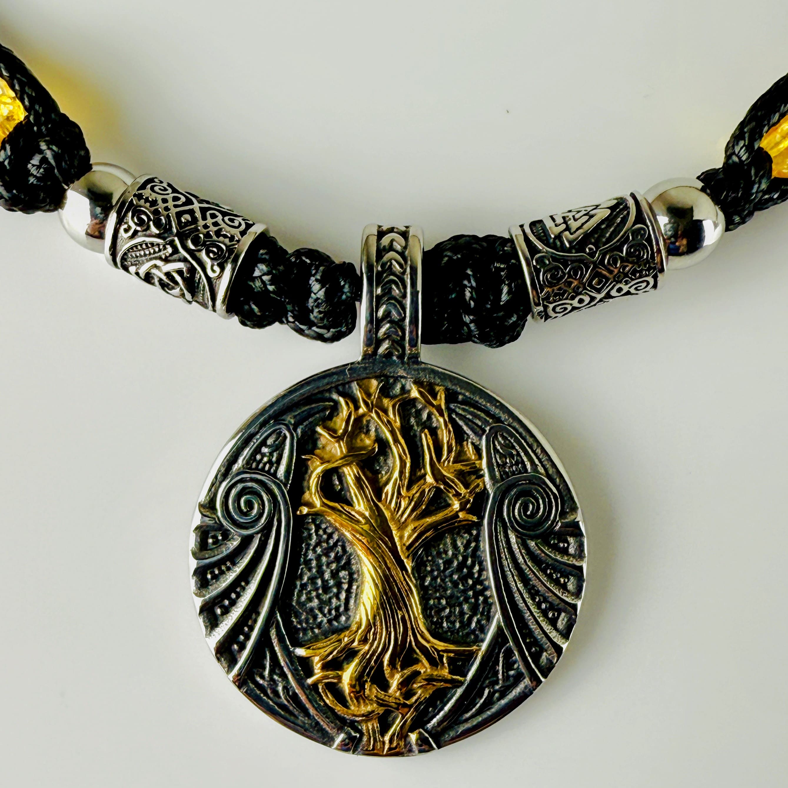 Handgeknüpfte Makramee-Kette mit funkelnden Citrin-Steinperlen, edlen Edelstahlelementen und einem kunstvoll verzierten Runenanhänger. Schweizer Schmuckstück, das Eleganz und Mystik verbindet.