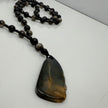 Handgefertigte Herren-Steinperlenkette mit matten Onyx-Perlen, schimmerndem Rauchquarz und einem großen geschliffenen Achat-Scheibenanhänger. Ein maskulines Accessoire, das Eleganz und Natürlichkeit verbindet.