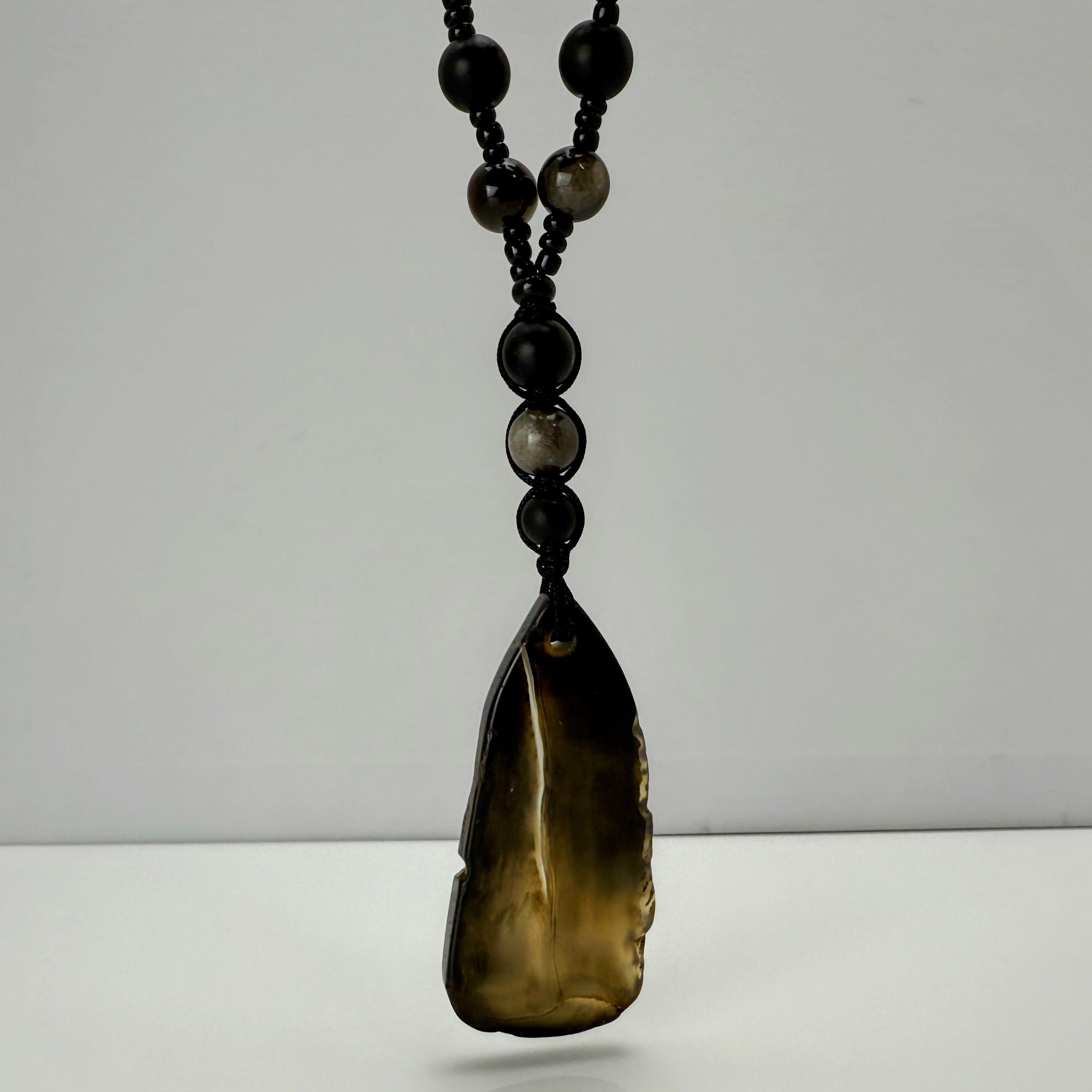 Handgefertigte Herren-Steinperlenkette mit matten Onyx-Perlen, schimmerndem Rauchquarz und einem großen geschliffenen Achat-Scheibenanhänger. Ein maskulines Accessoire, das Eleganz und Natürlichkeit verbindet.