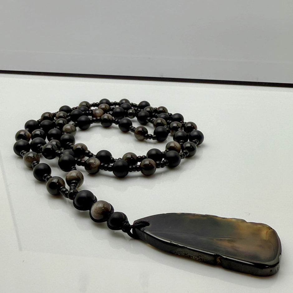 Handgefertigte Herren-Steinperlenkette mit matten Onyx-Perlen, schimmerndem Rauchquarz und einem großen geschliffenen Achat-Scheibenanhänger. Ein maskulines Accessoire, das Eleganz und Natürlichkeit verbindet.