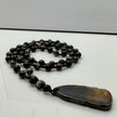 Handgefertigte Herren-Steinperlenkette mit matten Onyx-Perlen, schimmerndem Rauchquarz und einem großen geschliffenen Achat-Scheibenanhänger. Ein maskulines Accessoire, das Eleganz und Natürlichkeit verbindet.