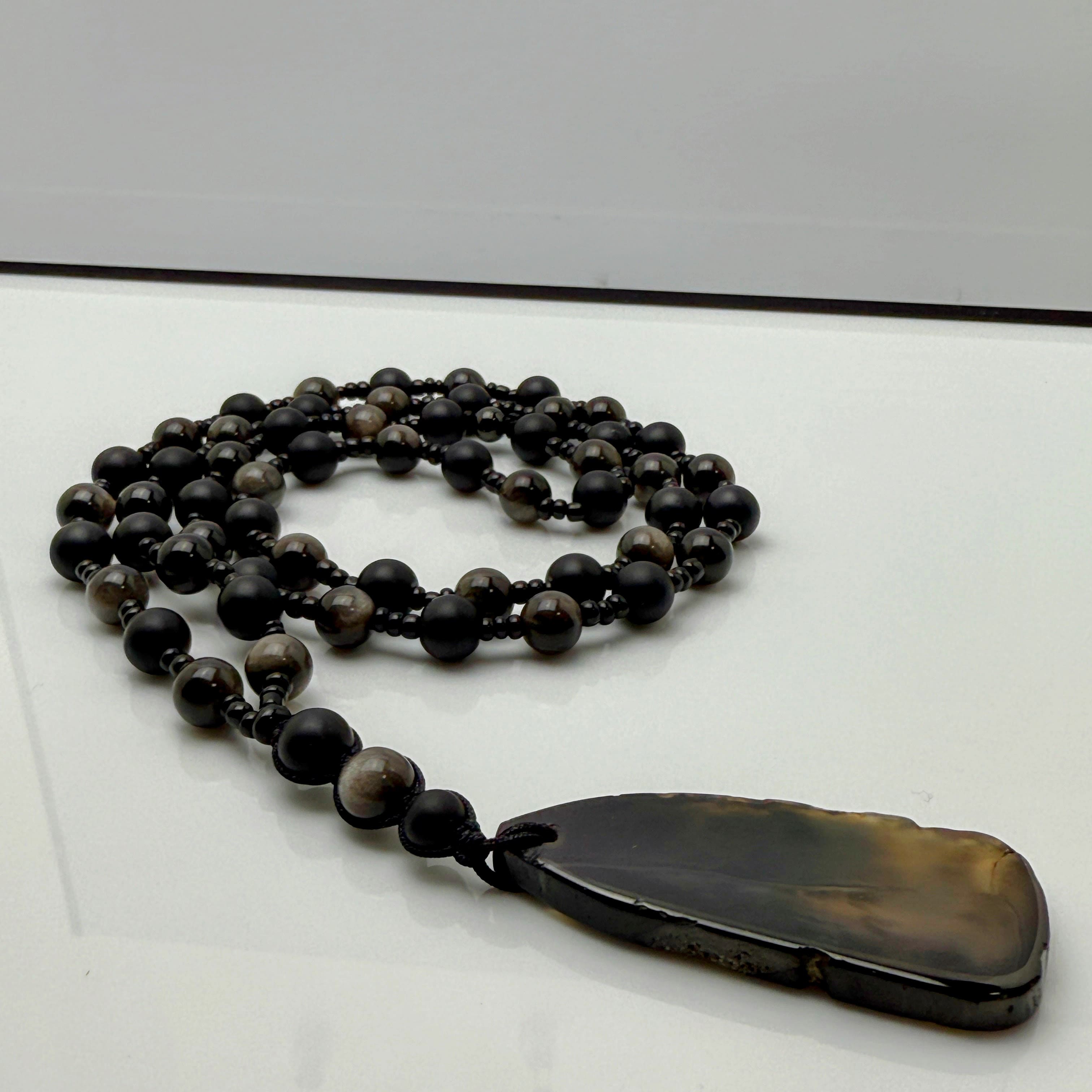 Handgefertigte Herren-Steinperlenkette mit matten Onyx-Perlen, schimmerndem Rauchquarz und einem großen geschliffenen Achat-Scheibenanhänger. Ein maskulines Accessoire, das Eleganz und Natürlichkeit verbindet.