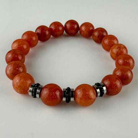 Handgefertigtes Armband mit leuchtenden Karneol-Quarz-Perlen in Orange-Rot, verziert mit eleganten Edelstahl-Elementen und funkelnden schwarzen Kristallakzenten. Ein modernes Accessoire mit lebendigen Farben und hochwertiger Verarbeitung.