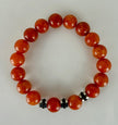 Handgefertigtes Armband mit leuchtenden Karneol-Quarz-Perlen in Orange-Rot, verziert mit eleganten Edelstahl-Elementen und funkelnden schwarzen Kristallakzenten. Ein modernes Accessoire mit lebendigen Farben und hochwertiger Verarbeitung.