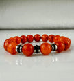 Handgefertigtes Armband mit leuchtenden Karneol-Quarz-Perlen in Orange-Rot, verziert mit eleganten Edelstahl-Elementen und funkelnden schwarzen Kristallakzenten. Ein modernes Accessoire mit lebendigen Farben und hochwertiger Verarbeitung.