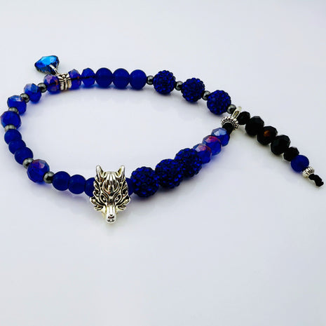 Sommerliches Fußkettchen mit facettierten blauen Glasperlen, Hämatit-Zwischenperlen, funkelnden Strassperlen und einem stilvollen Wolfskopf-Anhänger. Handgefertigt in der Schweiz, ideal für sommerliche Outfits und Barfußlooks am Strand.