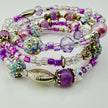 Handgefertigtes Spiralarmband in zarten Rosa- und Fliedertönen mit funkelnden Glasperlen, Strass-Elementen und filigranen Metall-Details. Flexibel und elegant, perfekt für besondere Anlässe und den Alltag.
