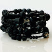 Elegantes spiralförmiges Armband mit einer vielseitigen Kombination aus schwarzen Glasperlen in verschiedenen Größen und Oberflächen. Handgefertigt in der Schweiz, flexibel ohne Verschluss, perfekt für stilvolle Alltagslooks und besondere Anlässe.