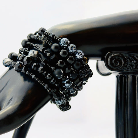 Elegantes spiralförmiges Armband mit einer vielseitigen Kombination aus schwarzen Glasperlen in verschiedenen Größen und Oberflächen. Handgefertigt in der Schweiz, flexibel ohne Verschluss, perfekt für stilvolle Alltagslooks und besondere Anlässe.