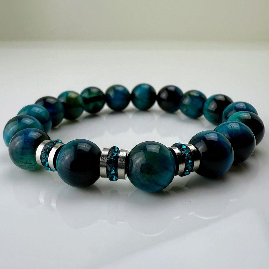 Blaugrünes Tigeraugen-Armband mit funkelnden Kristall-Edelstahl-Elementen, handgefertigt in der Schweiz. Vielseitiges und elegantes Design, das Strapazierfähigkeit und Stil vereint.