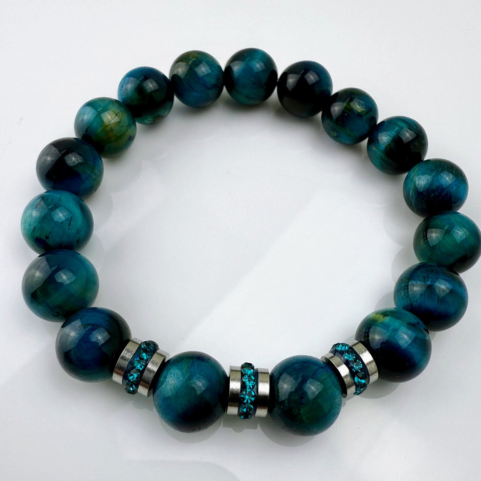 Blaugrünes Tigeraugen-Armband mit funkelnden Kristall-Edelstahl-Elementen, handgefertigt in der Schweiz. Vielseitiges und elegantes Design, das Strapazierfähigkeit und Stil vereint.
