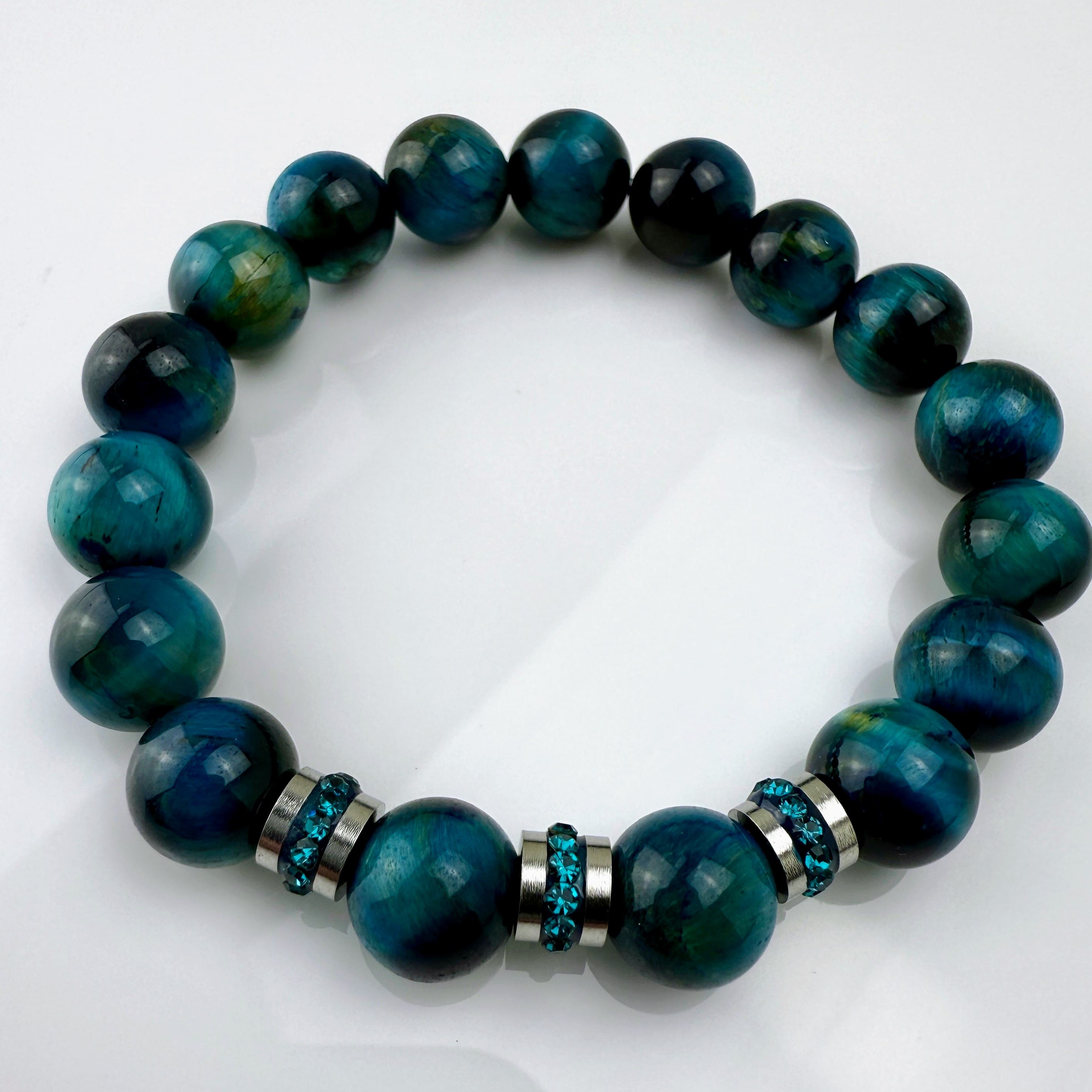 Blaugrünes Tigeraugen-Armband mit funkelnden Kristall-Edelstahl-Elementen, handgefertigt in der Schweiz. Vielseitiges und elegantes Design, das Strapazierfähigkeit und Stil vereint.