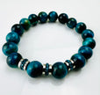 Blaugrünes Tigeraugen-Armband mit funkelnden Kristall-Edelstahl-Elementen, handgefertigt in der Schweiz. Vielseitiges und elegantes Design, das Strapazierfähigkeit und Stil vereint.