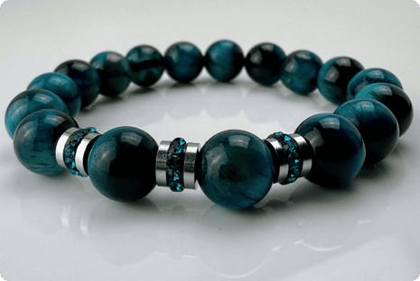 Blaugrünes Tigeraugen-Armband mit funkelnden Kristall-Edelstahl-Elementen, handgefertigt in der Schweiz. Vielseitiges und elegantes Design, das Strapazierfähigkeit und Stil vereint.