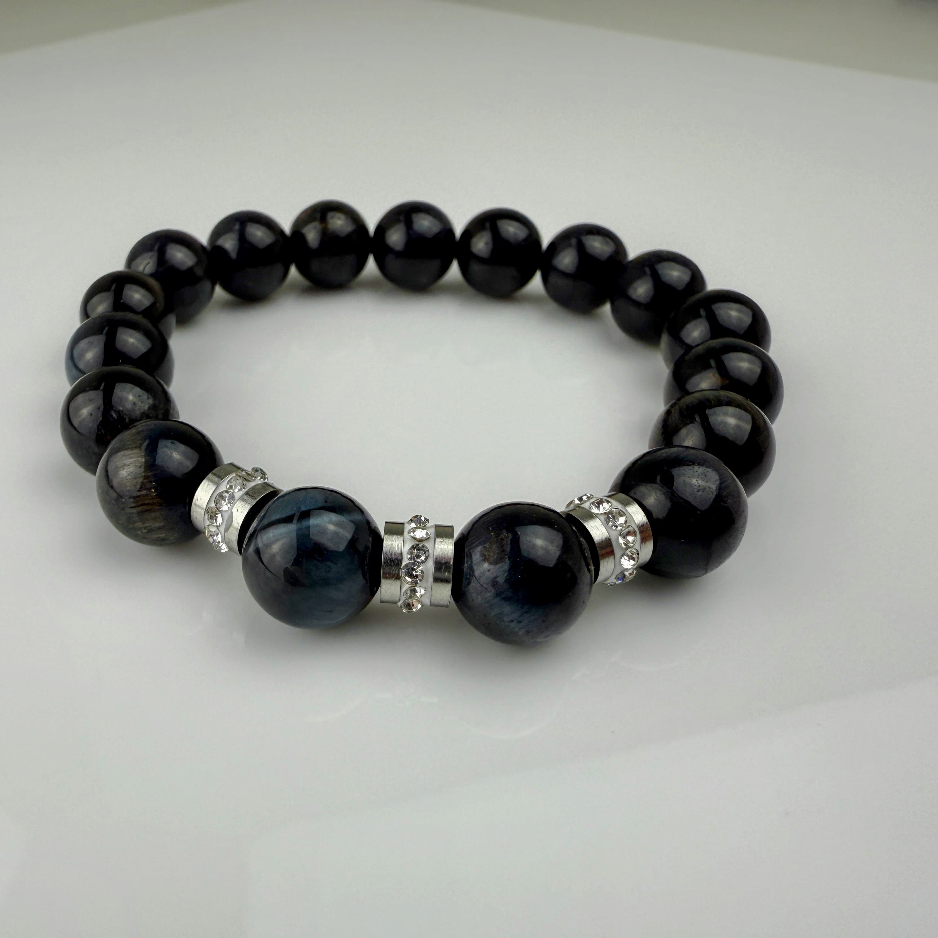 Schwarzes Tigeraugen-Armband mit funkelnden Edelstahl-Elementen und klaren Kristallen, handgefertigt in der Schweiz. Elegantes und modernes Design, perfekt für jeden Anlass.