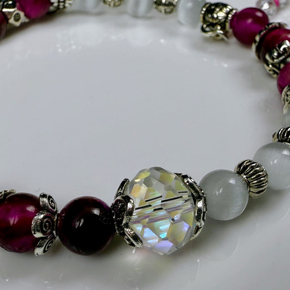 Verspieltes Damenarmband mit Anhängern wie Teddybär, Blüten und Schmuckelementen, kombiniert mit weißen und weinroten Perlen, ideal als verspieltes Accessoire.