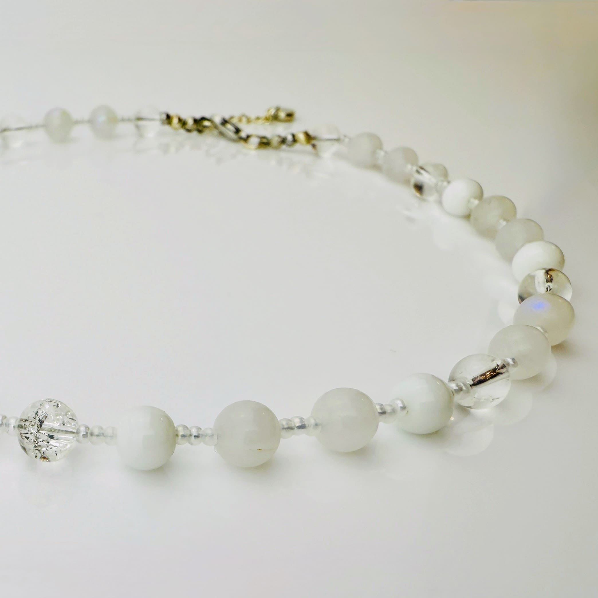 Zierliche Damenhalskette aus Mondstein- und Achatperlen, kombiniert mit transparent-weißen Rocailles. Handgefertigtes Schmuckstück aus der Schweiz, ideal für minimalistische und elegante Outfits.