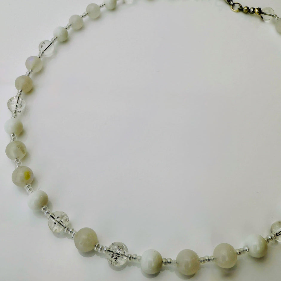 Zierliche Damenhalskette aus Mondstein- und Achatperlen, kombiniert mit transparent-weißen Rocailles. Handgefertigtes Schmuckstück aus der Schweiz, ideal für minimalistische und elegante Outfits.