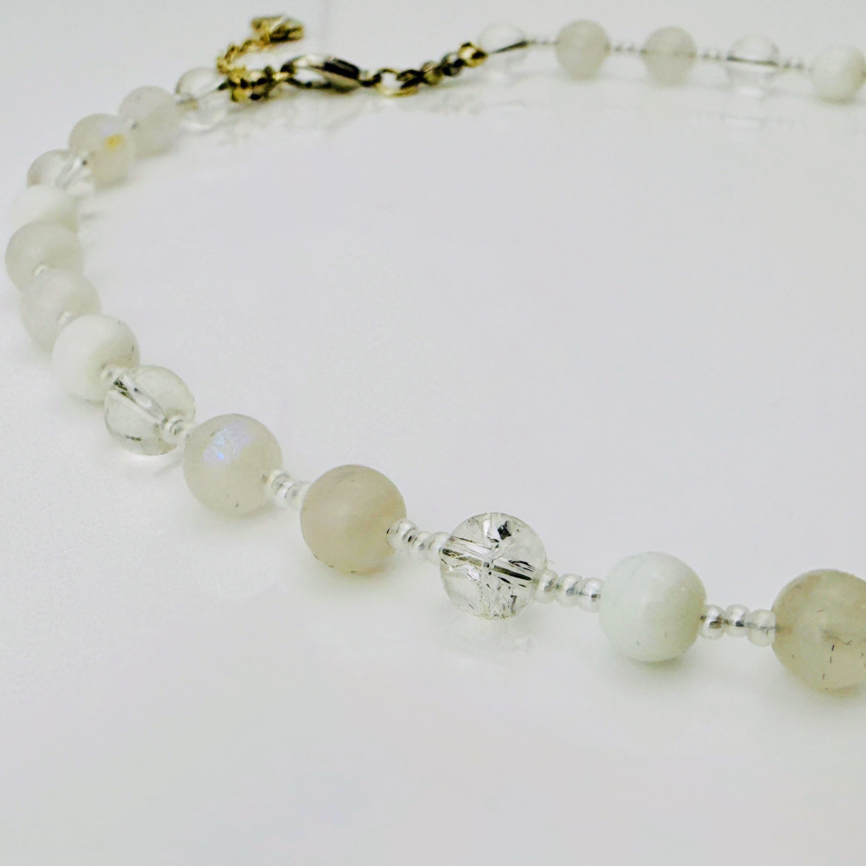 Zierliche Damenhalskette aus Mondstein- und Achatperlen, kombiniert mit transparent-weißen Rocailles. Handgefertigtes Schmuckstück aus der Schweiz, ideal für minimalistische und elegante Outfits.