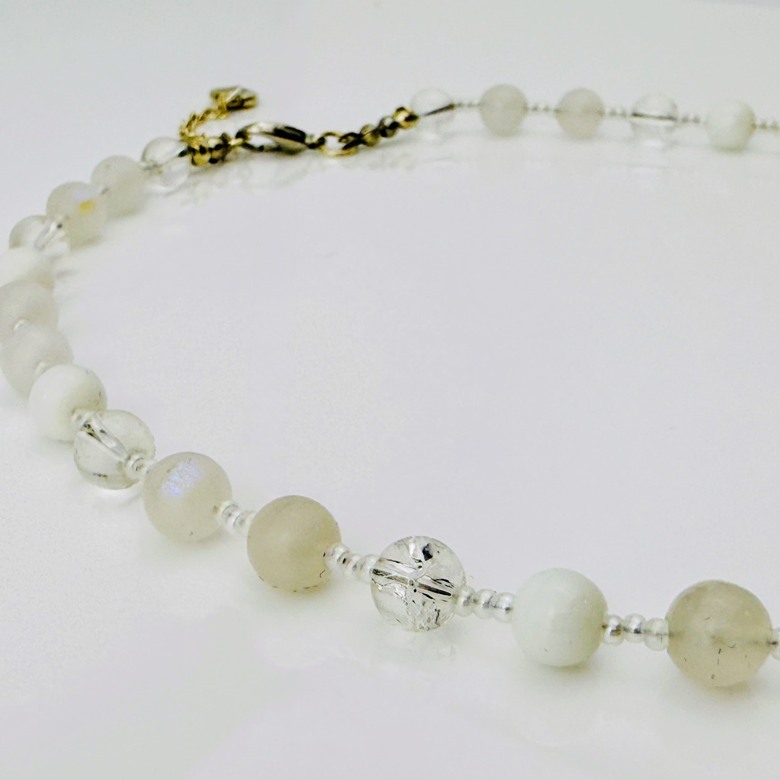 Zierliche Damenhalskette aus Mondstein- und Achatperlen, kombiniert mit transparent-weißen Rocailles. Handgefertigtes Schmuckstück aus der Schweiz, ideal für minimalistische und elegante Outfits.